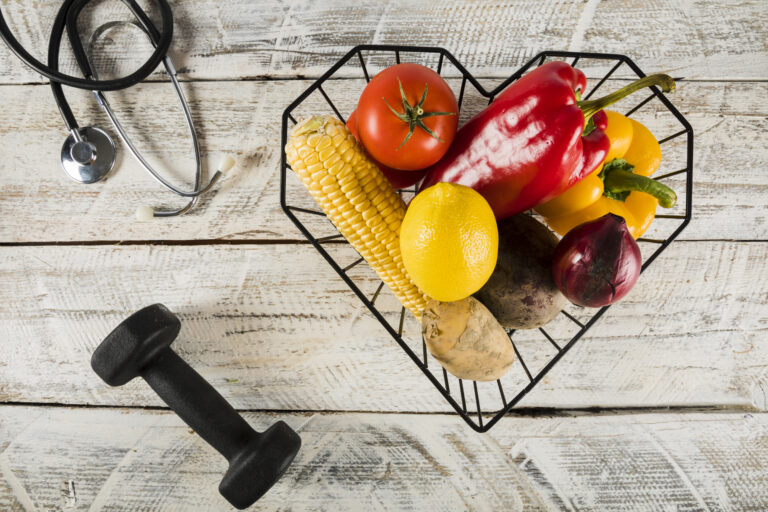 colorful-raw-vegetables-container-near-dumbbell-stethoscope-wooden-surface