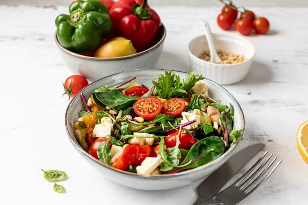 A plate with baked peppers, beans and tomatoes on a white background.